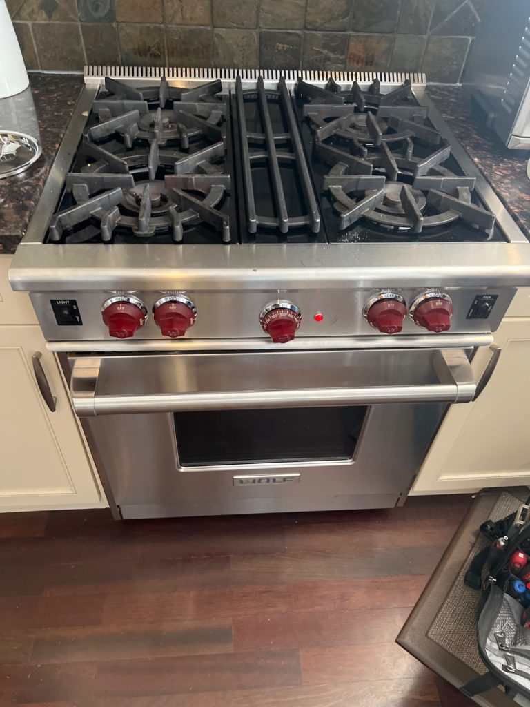 Wolf gas professional range with red knobs restored to full operation after igniter and thermostat replacement in a Springbank Hill kitchen, Calgary