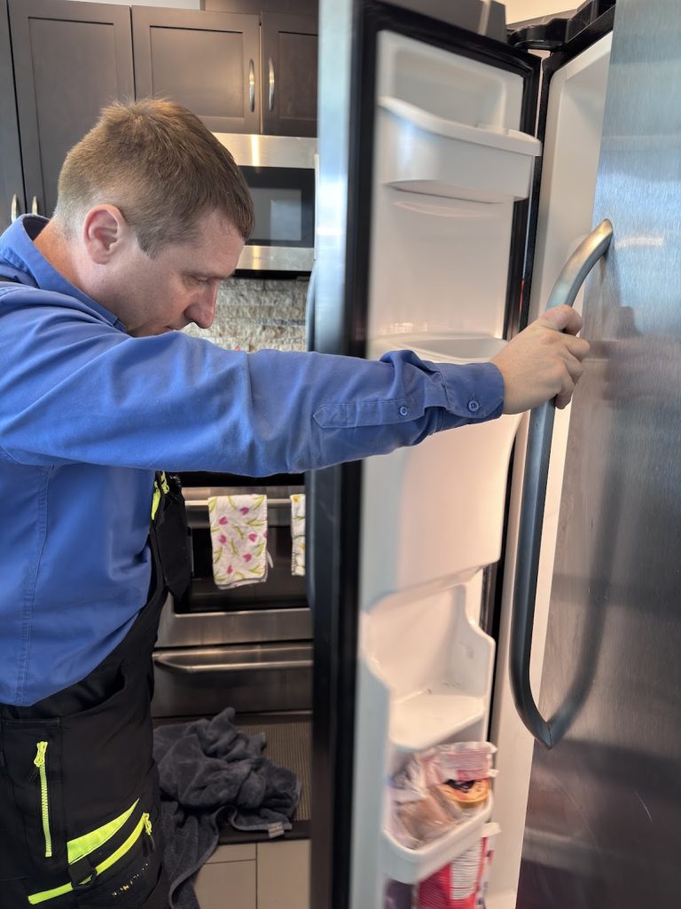 TechVill technician Alex inspecting the fresh food compartment of a Frigidaire FFHF2322MFD French door refrigerator in a Beltline kitchen, Calgary