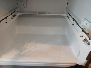 Maytag refrigerator evaporator drain hole accessed for unclog during service in Lincoln Park, Calgary