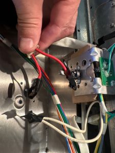 TechVill technician working through the thermostat wiring connections during griddle thermostat replacement on a GE Monogram pro range in Priddis, AB