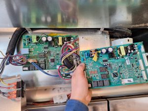 Failed and replacement GE Monogram control boards compared side by side during built-in refrigerator repair in Inglewood, Calgary