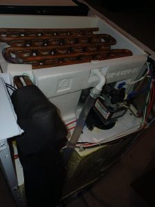 Scotsman ice maker pulled out for service in Inglewood, Calgary, showing the copper condenser coils, condenser fan motor, water tubing and wiring harness at the back of the unit