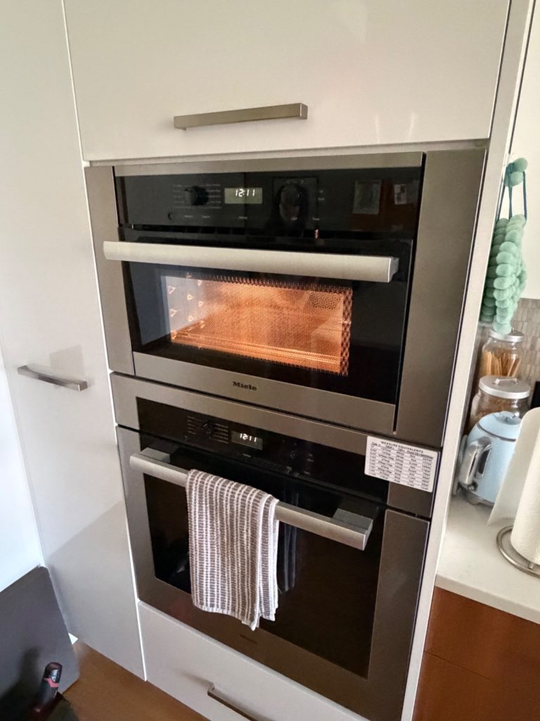 Miele built-in speed oven above a wall oven in white cabinetry during magnetron diagnosis in inner southwest Calgary