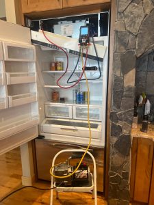 TechVill technician accessing the green UI control wiring harness on a Viking built-in refrigerator in Silvertip, Canmore