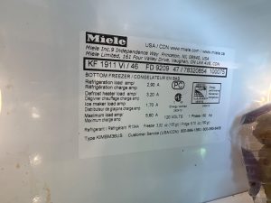 Miele KF1911Vi/46 built-in refrigerator rating plate showing model number and R134a refrigerant charge during a TechVill diagnosis in Priddis, Foothills County