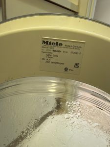 Motor housing exposed on a Miele W1612 washing machine, showing the commutator motor that drives the drum