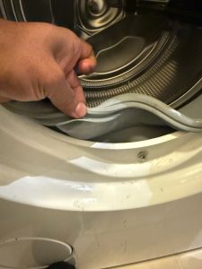TechVill technician accessing the rear panel of a Miele W1612 front-load washer in Brighouse, Richmond BC, to diagnose a no-spin symptom