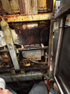 Commercial fryer cabinet after partial removal of oil-soaked burner insulation during a Vancouver service visit