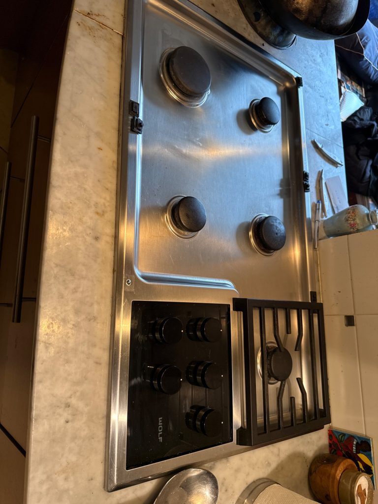 TechVill technician cleaning the burner ports on a Wolf CG365T/S 36-inch gas cooktop in Altamont, West Vancouver, before diagnosing ignition components