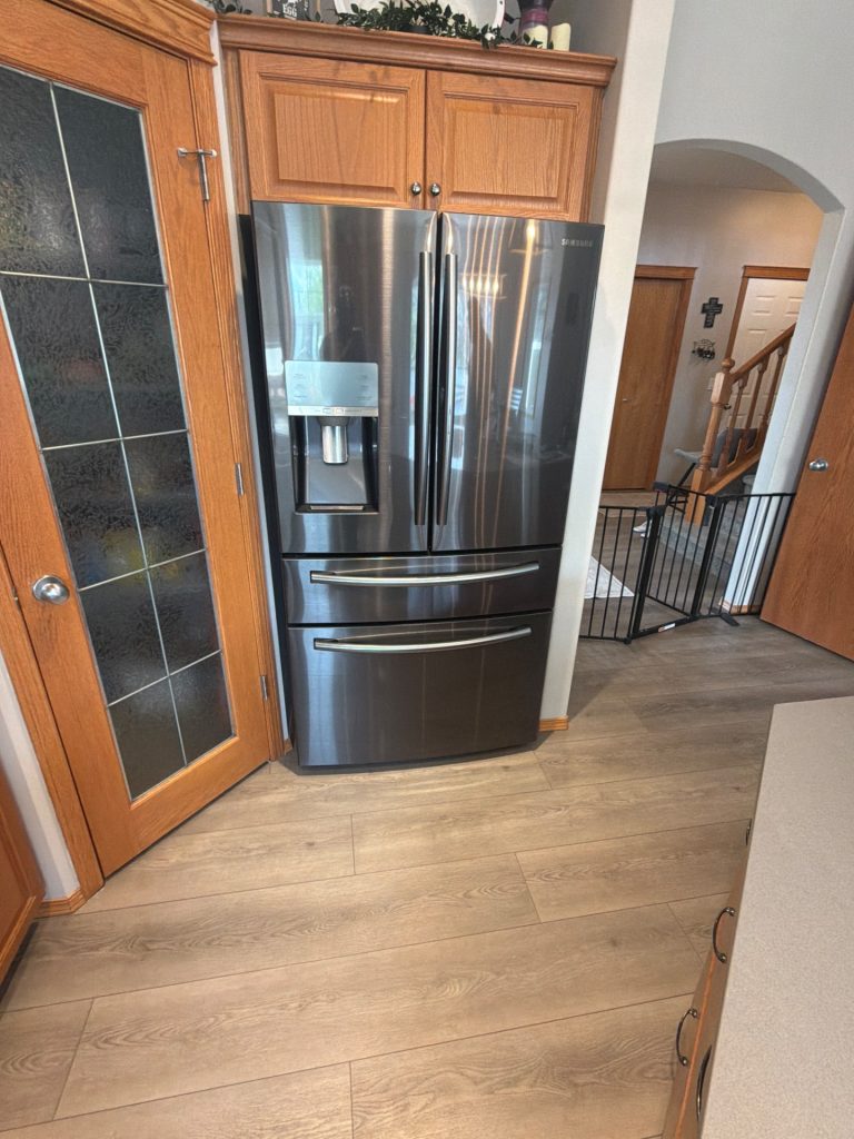 Samsung black stainless French-door refrigerator installed in a Coopers community kitchen in Airdrie, AB