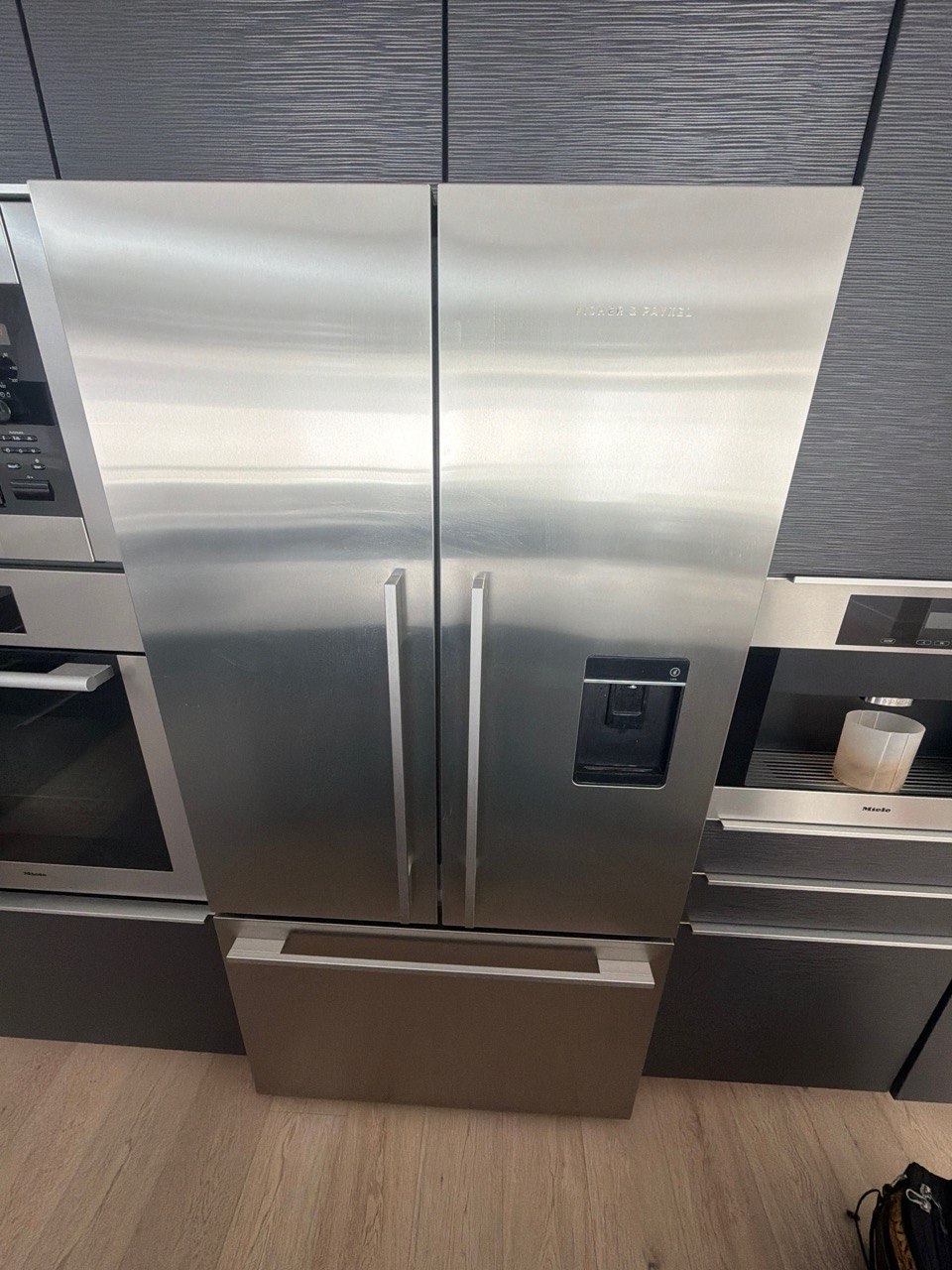 Fisher & Paykel RF201ADUSX5n stainless steel French-door refrigerator with a through-the-door ice and water dispenser, installed in a Tuscany kitchen in NW Calgary