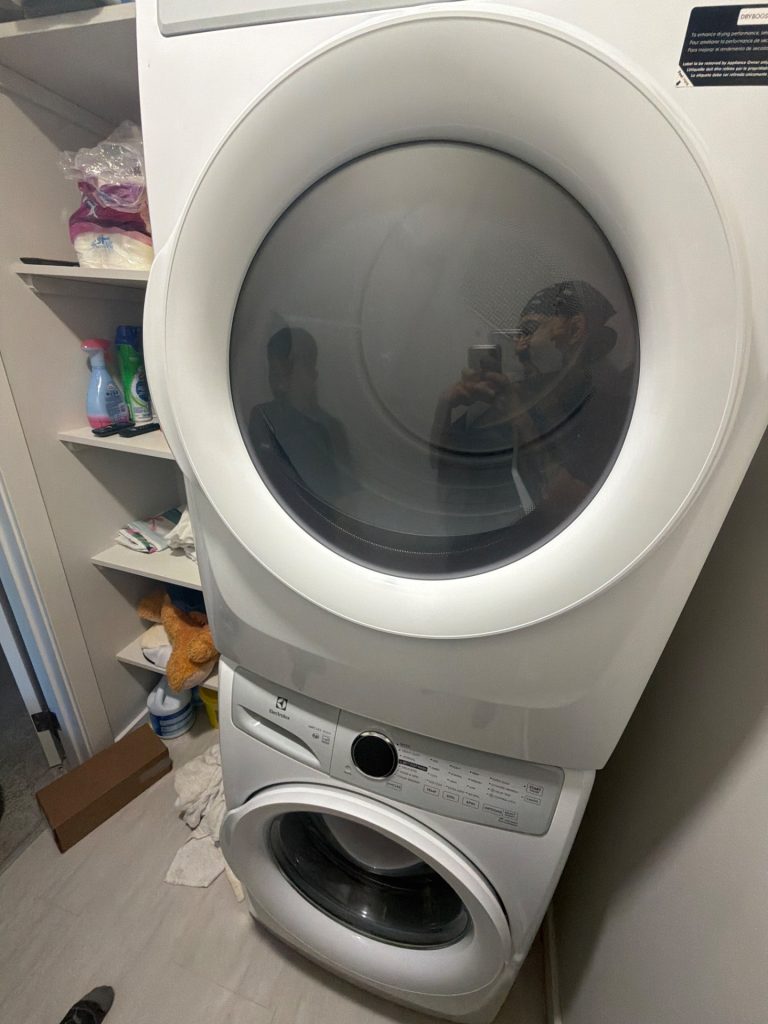 Stacked Electrolux washer and dryer in a Livingston, Calgary laundry closet, with the washer mounted below the dryer ahead of drain pump service by TechVill.