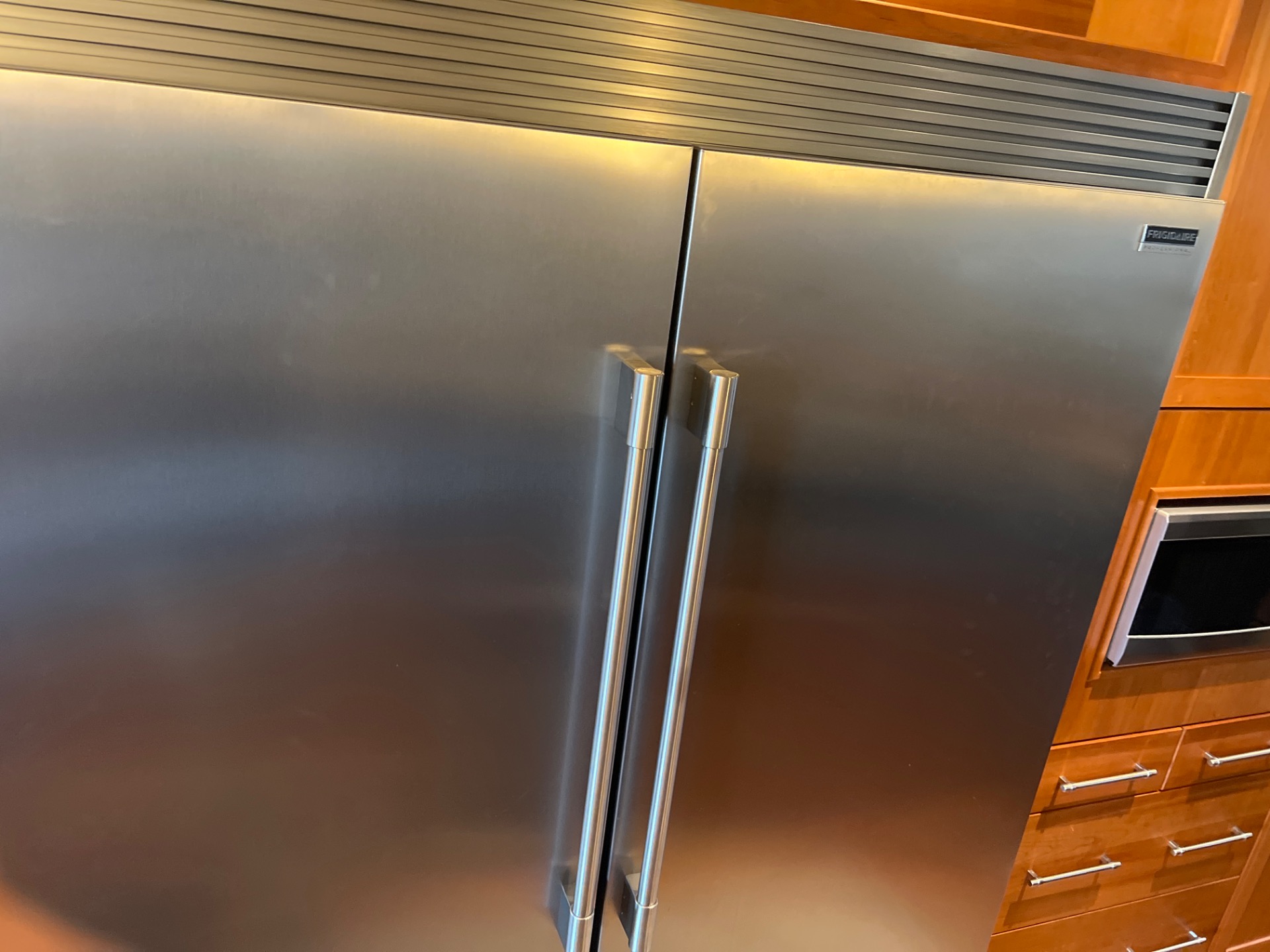 Stainless steel Frigidaire Professional built-in refrigerator integrated into wood cabinetry in a Central Canmore home during a sealed-system rebuild