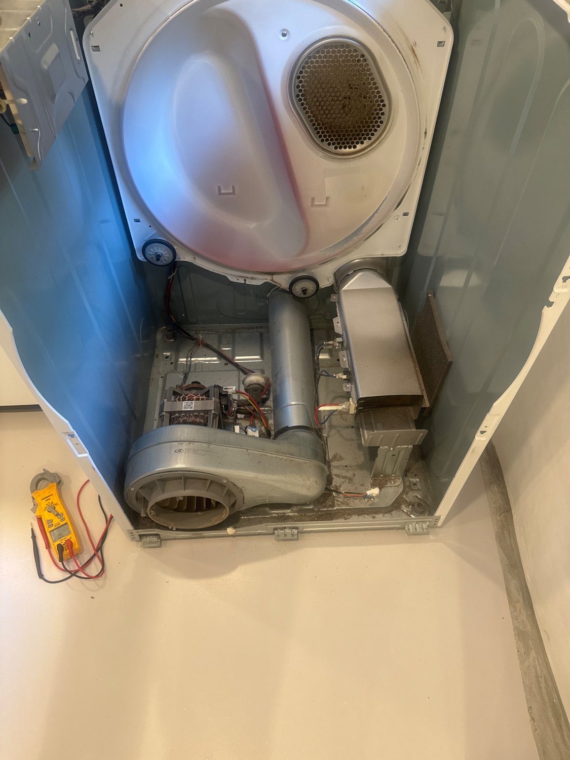 Samsung dryer opened at the base showing the blower housing, heating assembly, and a clamp meter during the North Vancouver diagnosis