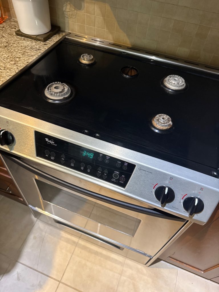 TechVill technician diagnosing two cooktop burners on a Maytag gas range in Central Lonsdale North Vancouver