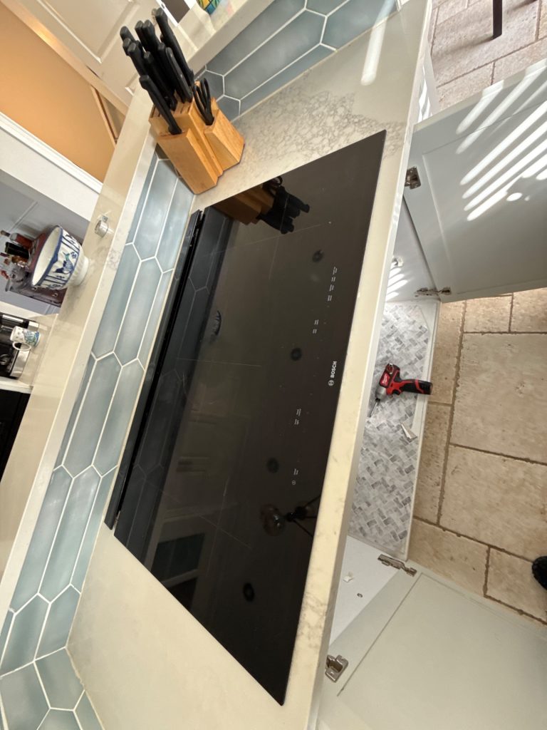 TechVill technicians removing an existing downdraft vent during a KitchenAid install in Findlay Creek Ottawa