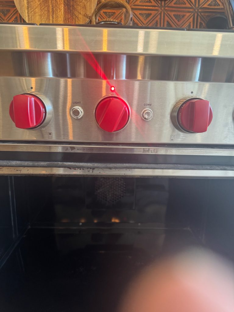Wolf GR366 gas range control panel with the oven dial set to OFF and the indicator light still lit in a Rocky View County kitchen