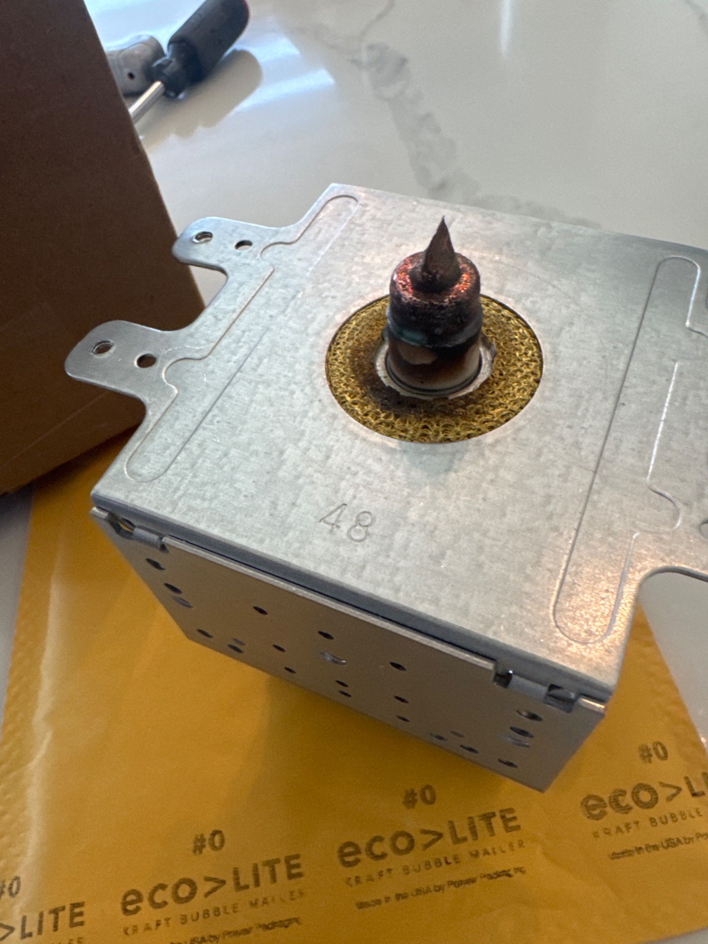 Failed KitchenAid microwave magnetron removed during repair, showing an arced and burnt antenna cap