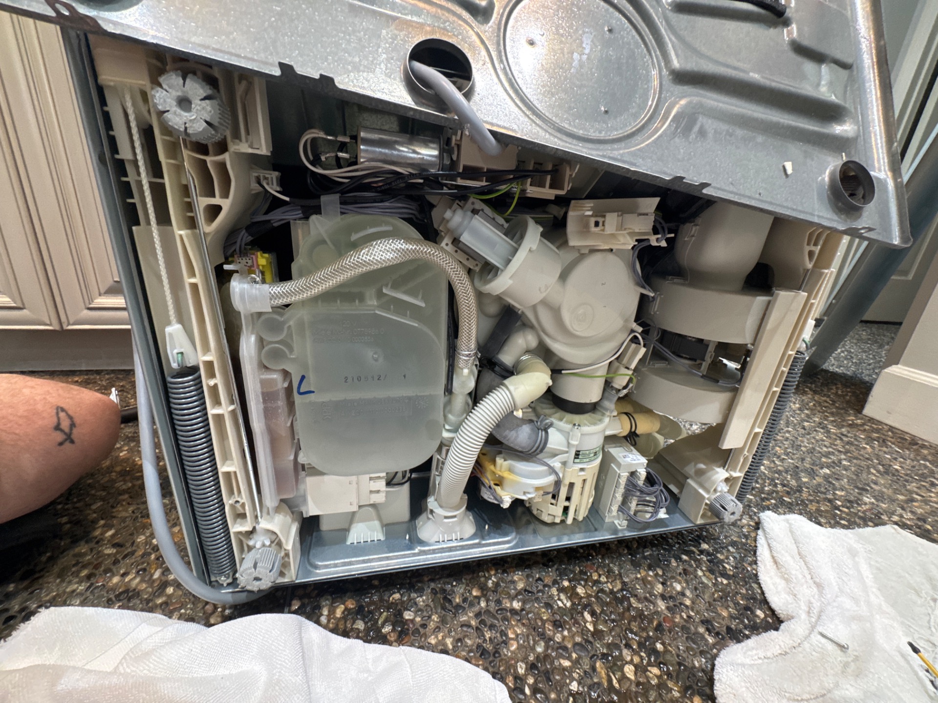 Miele dishwasher uninstalled with its base removed, exposing the pump, hoses, water intake valve and salt container during a leak inspection in Vancouver