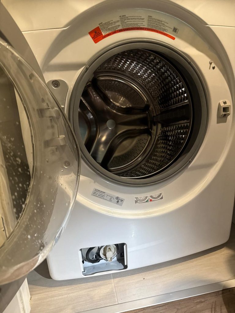 Samsung stacked washer open for service with the lower access panel removed in a downtown Calgary condo