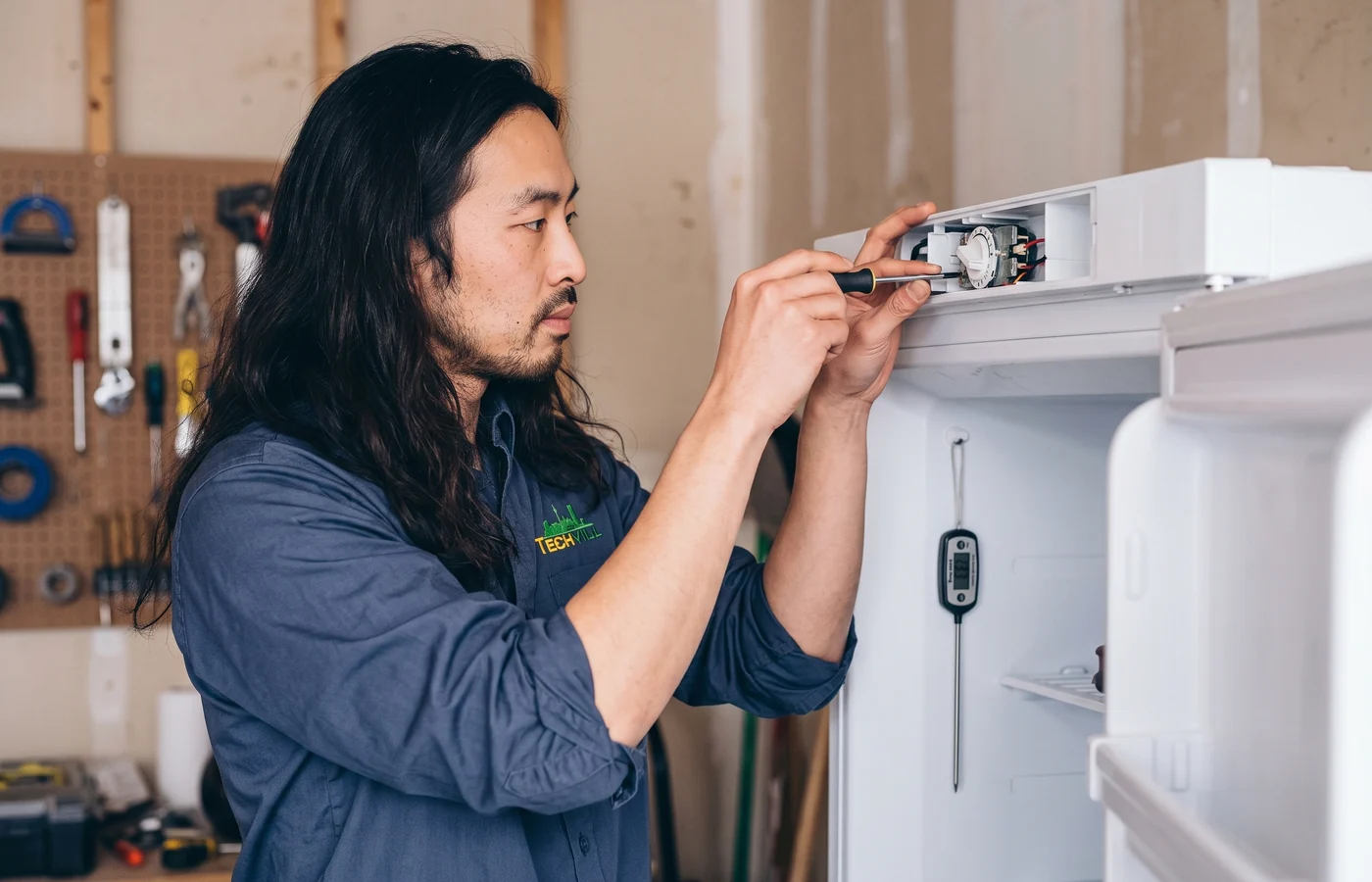 TechVill technician repairing a garage-ready freezer