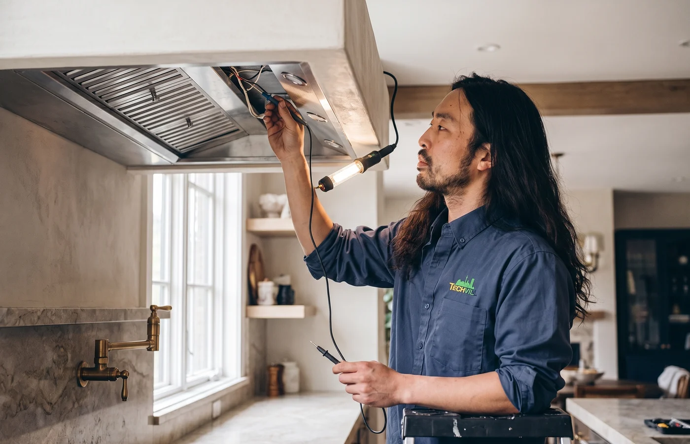 TechVill technician repairing an insert hood fan