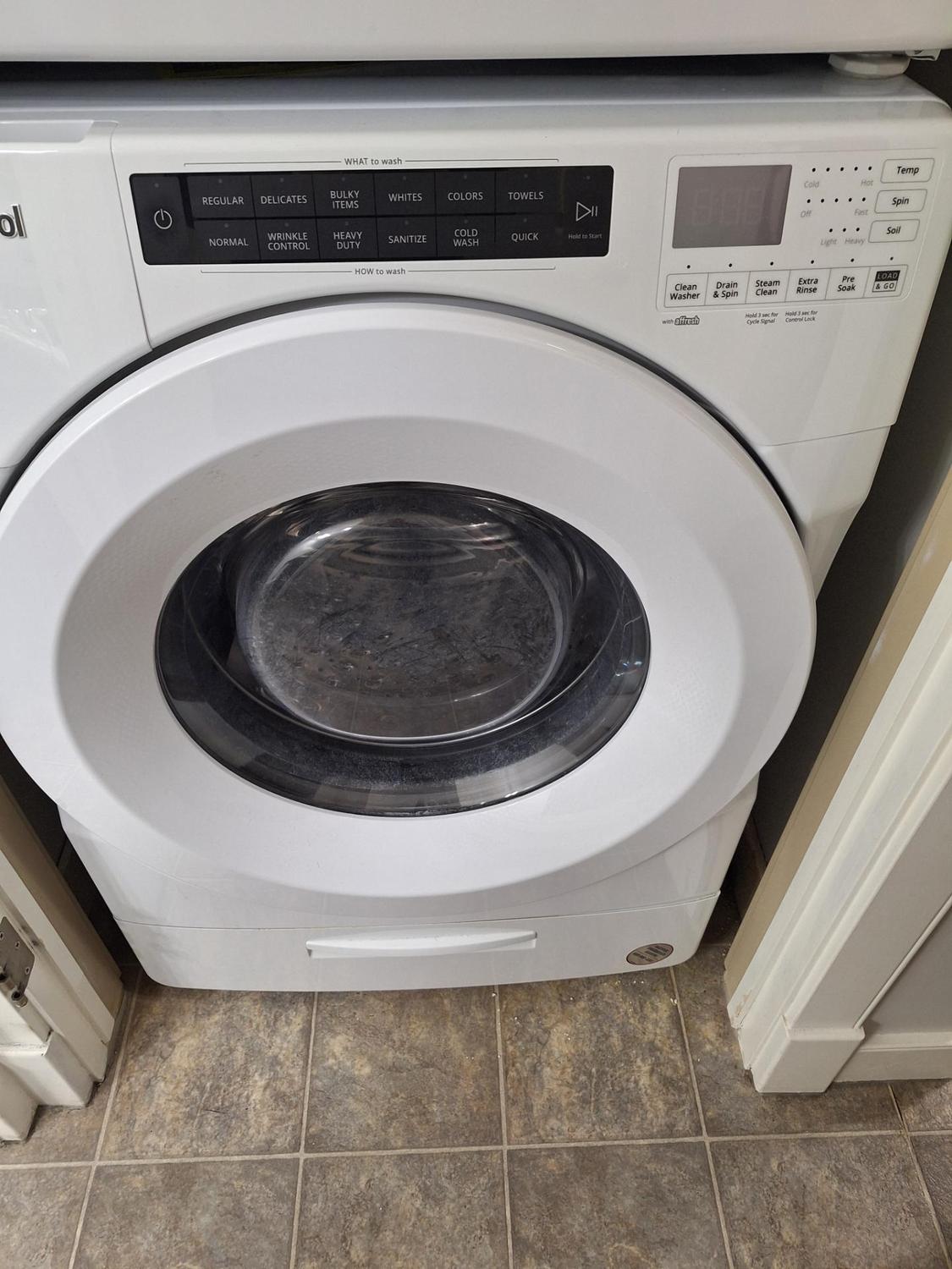 Whirlpool front-load washing machine on a pedestal in a Calgary condo laundry area after inlet valve replacement