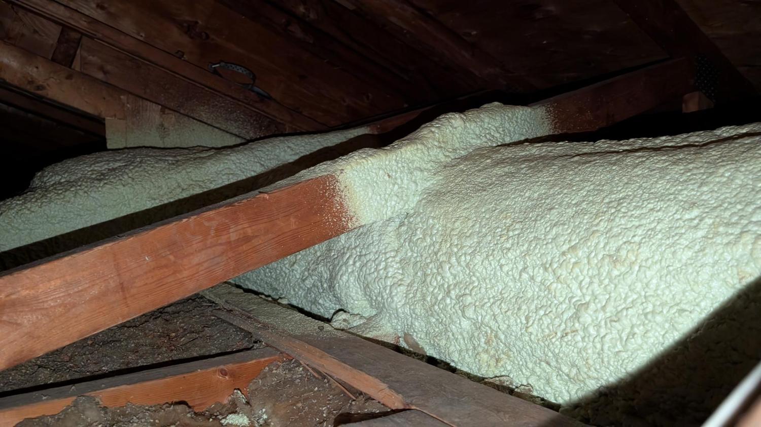 Attic joists and spray-foam insulation inspected to plan a range hood exhaust duct route in an east Ottawa home